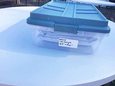 60 inch x 126 inch white rectangle tablecloths pulled directly from storage tote and put onto eight-foot rectangle tables