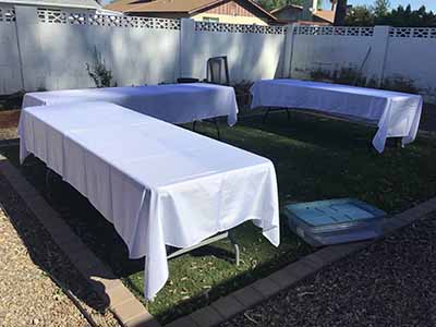 60 inch x 126 inch white rectangle tablecloths pulled directly from storage tote and put onto eight-foot rectangle tables