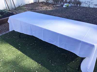 60 inch x 126 inch white rectangle tablecloths pulled directly from storage tote and put onto eight-foot rectangle tables