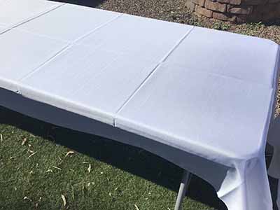 60 inch x 126 inch white rectangle tablecloths pulled directly from storage tote and put onto eight-foot rectangle tables