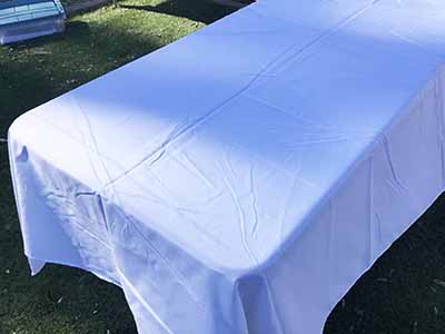 60 inch x 126 inch white rectangle tablecloths pulled directly from storage tote and put onto eight-foot rectangle tables